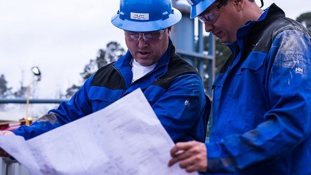 Two men with blue Alfa Laval jackets and helmets at a production site