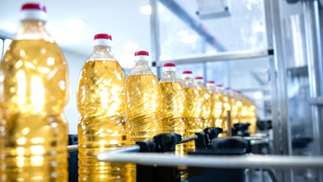 Plastic bottles filled with cooking oil on a production line in a factory.