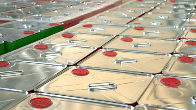 Rows of metal containers with red caps and handles, arranged closely together