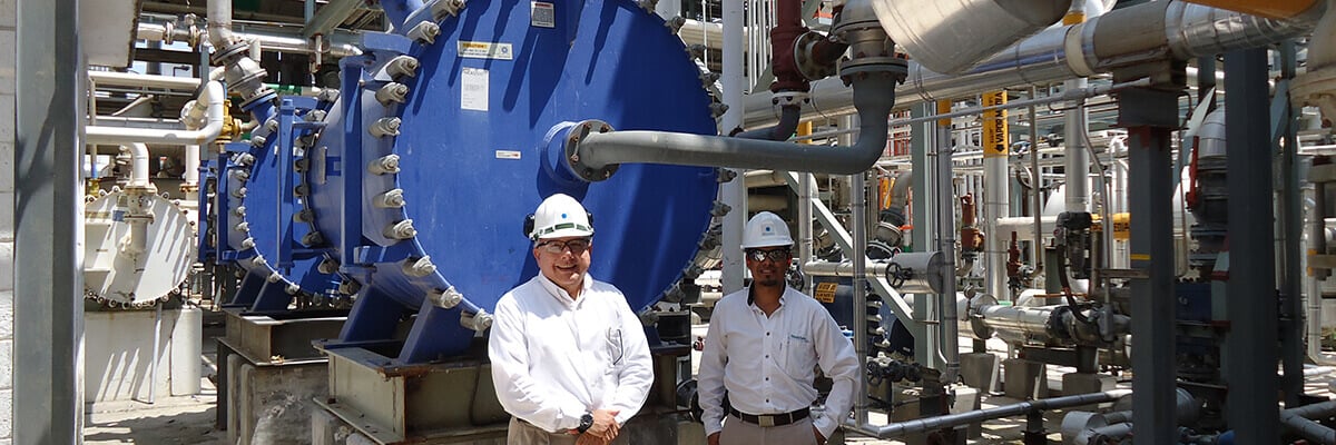 two men standing in front of a spiral heat exchanger installation