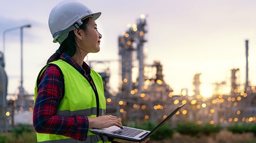 female engineer with laptop outside chemical plant