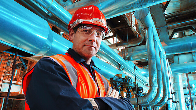 Engineer in front of blue industrial pipes