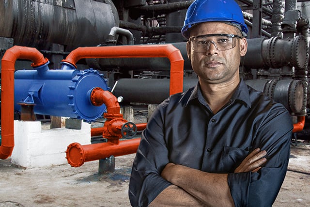 Man wearing hard hat and safety glasses with crossed arms in front of an installed Alfa Laval welded spiral heat exchanger