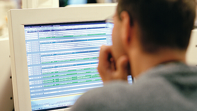 man seen from behind sitting in front of computer