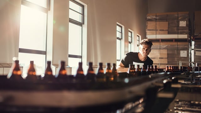 man-inspecting-beer-bottles-brewery-conveyor-belt-sunlight-industrial-packaging.jpg